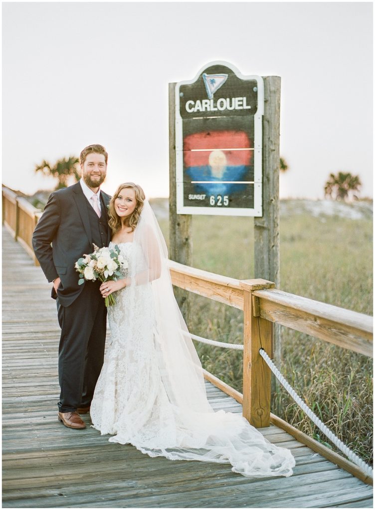 bride and groom next to beach sign