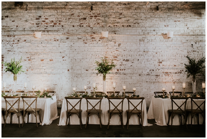 reception white brick with table greenery and wood chairs 
